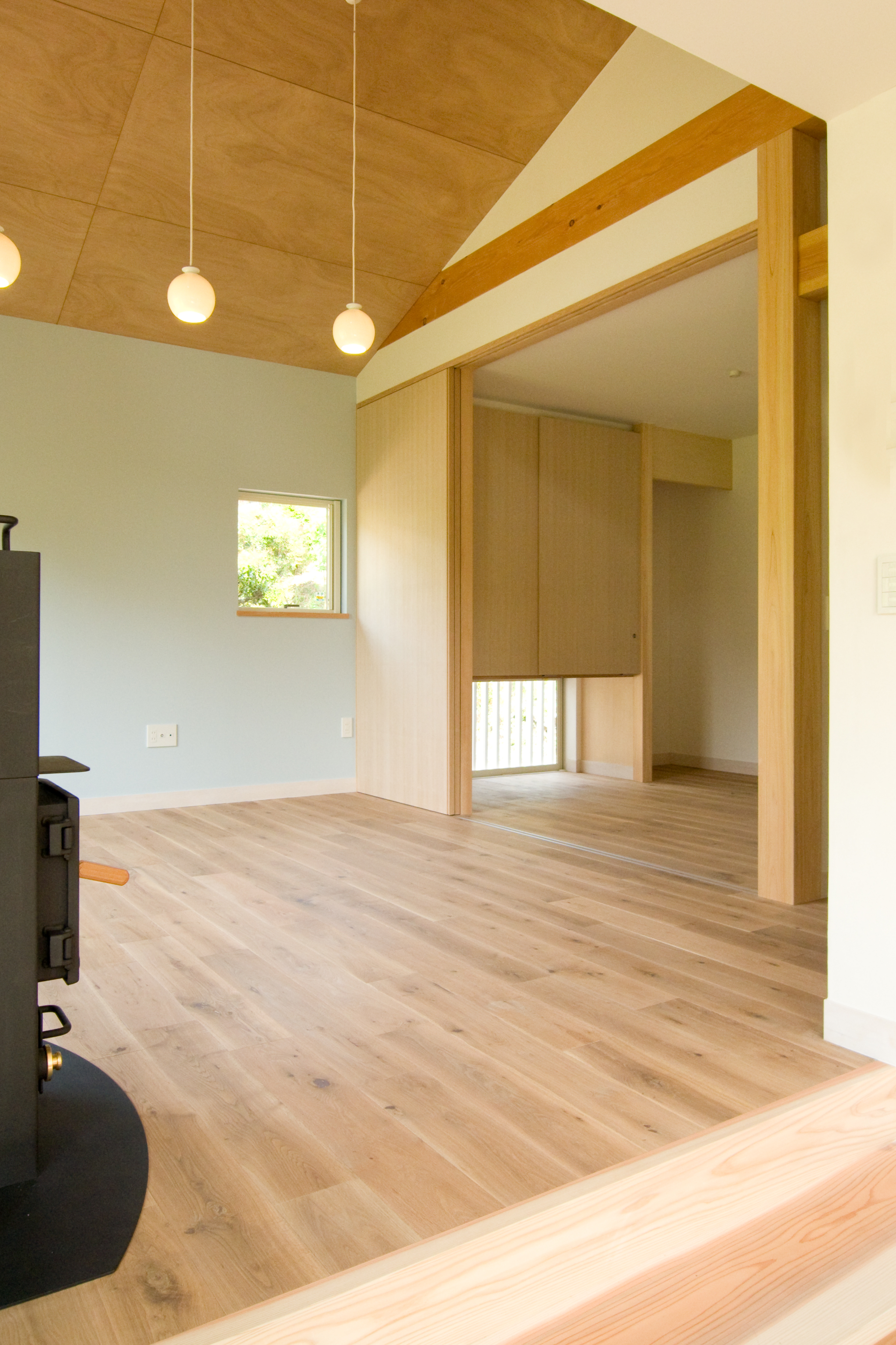 ダイニングからリビング方向＿ラワン目透し貼天井と水色のアクセントウォールとオーク無垢厚板フローリング